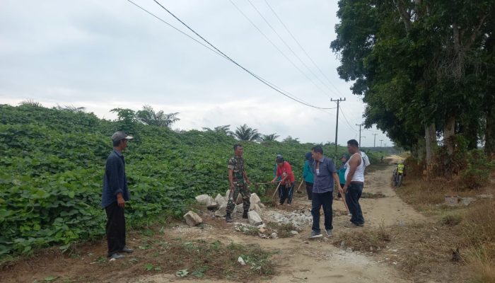 Semangat Gotong Royong, Babinsa Koramil Tanah Jawa Bantu Perbaikan Jalan Demi Kelancaran Warga